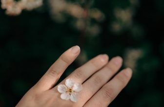 close up of woman holding a delicate flower between her fingers